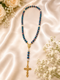 Handcrafted blue and pink marbled rosary displayed on champagne satin with ivory roses and baby's breath